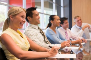 Five businesspeople at boardroom table smiling