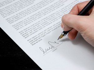 A shot of an individuals hand signing their name with a fountain pen