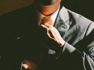 Man straightening tie when wearing a suit