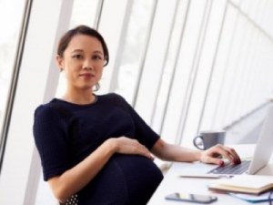 pregnant woman at her desk featured